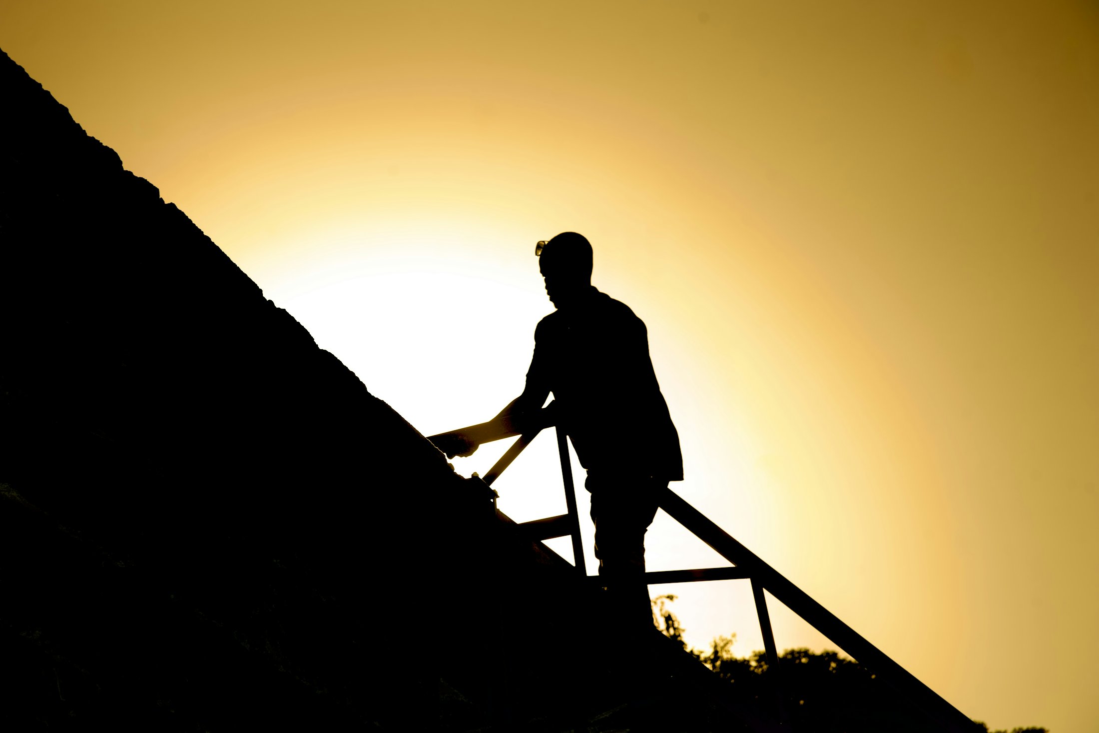 Silhouette of a roofer working at golden hour