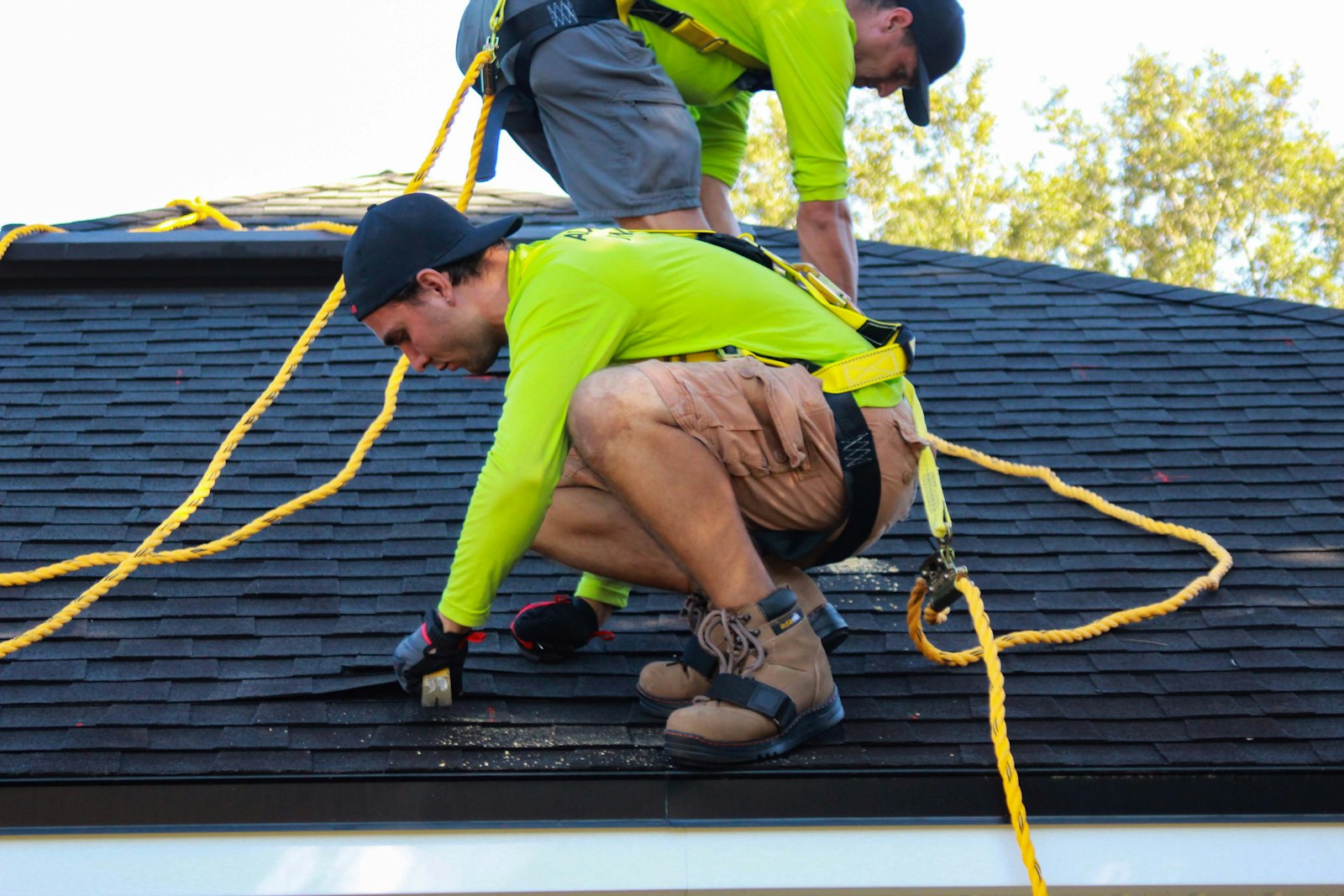 Roofing crew installing standard dark architectural asphalt shingles on a new home